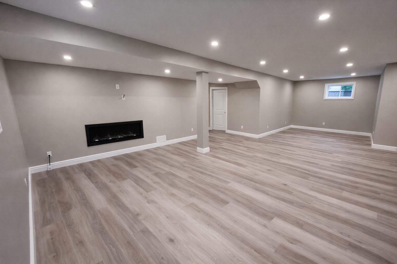 Finished basement with grey vinyl plank flooring and pot lights