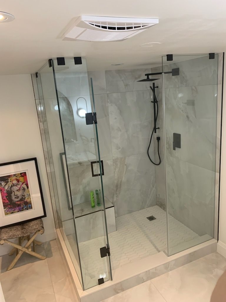 Marble bathroom with a glass walk-in shower and matte black fixtures, portrait view
