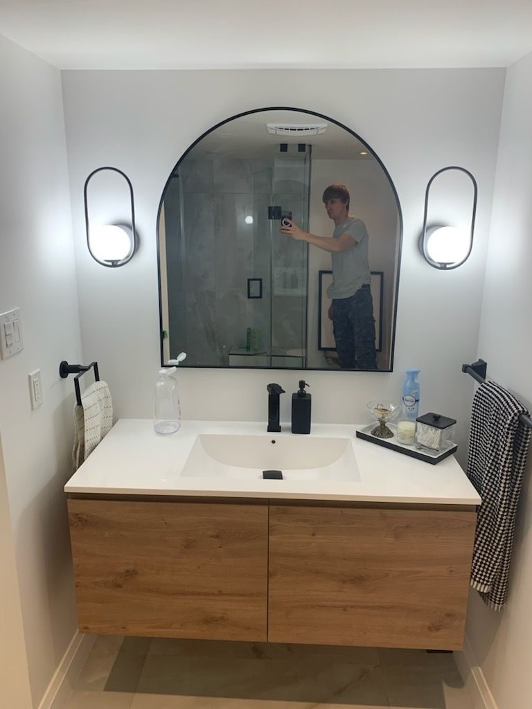 Bathroom with a floating wood vanity and an arched mirror, portrait view