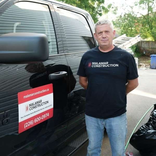 Dave Cuthbert, Co-Owner and Project Manager, beside the Malamar Construction van