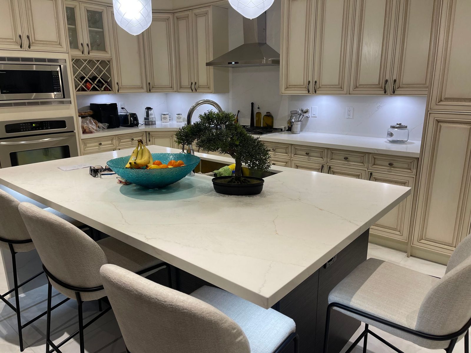 Custom kitchen with cream cabinets, a large island, counter stools and pendant lighting