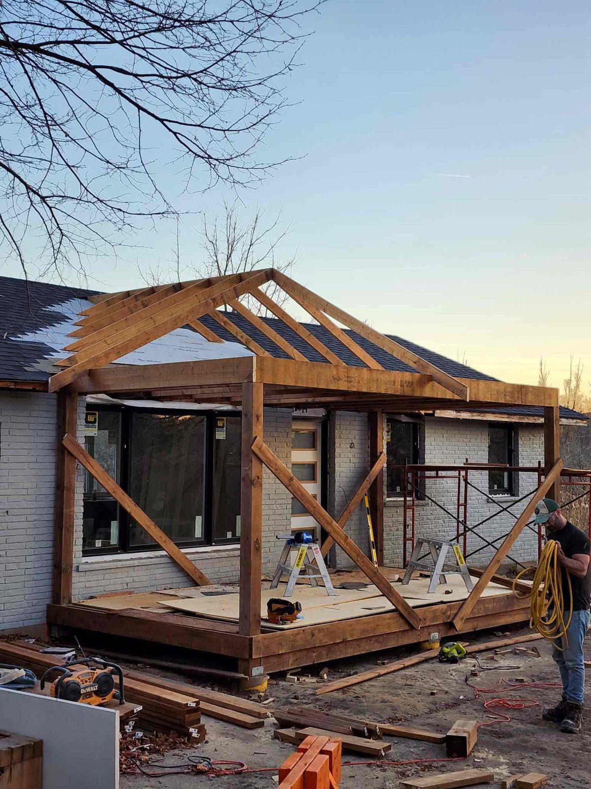 Timber-frame home addition under construction at sunset