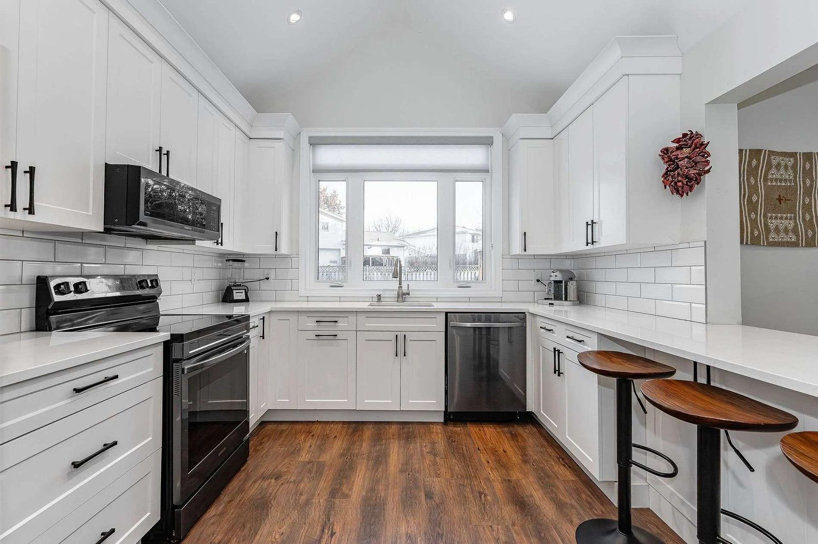White kitchen with a black island, brass pendants and wood floor