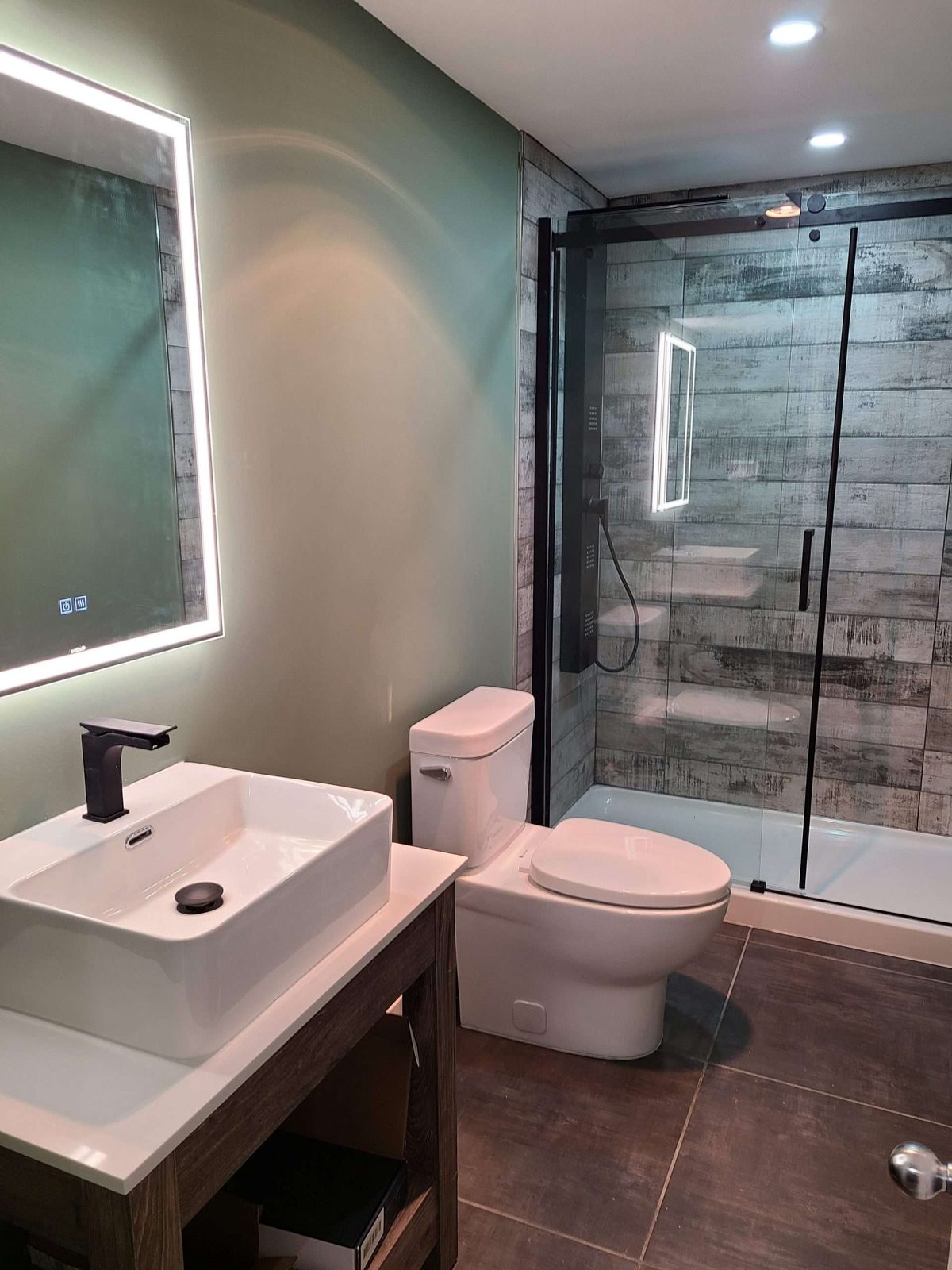 Moody green-walled bathroom with a backlit round mirror